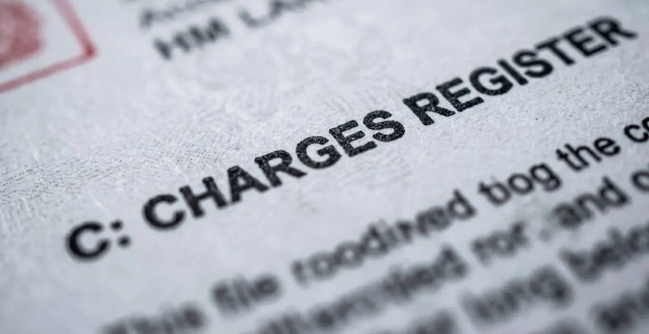 Extreme close-up of an official UK Land Registry title register document showing the Charges Register section with subtle focus on administrative formatting, representing the critical due diligence required when purchasing property