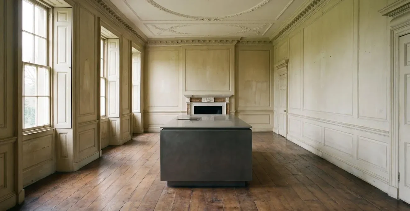 Contemporary freestanding kitchen island positioned within historic manor house interior preserving original architectural features